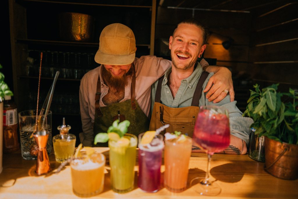 Friendly Bartenders Smiling and Preparing Colorful Cocktails in a Cozy Bar